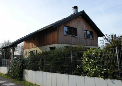Zweifamilienhaus mit vergrauter Lärchenschalung und grünen Fenstern